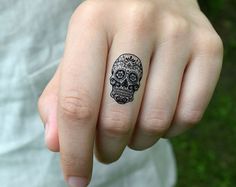 a person with a skull tattoo on their finger