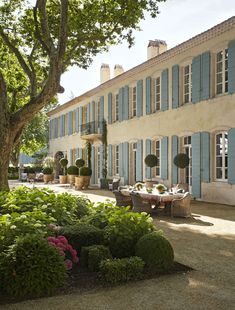 a large house with blue shutters on the front and side windows, surrounded by greenery