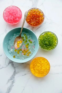 three bowls filled with gummy bears and two spoons