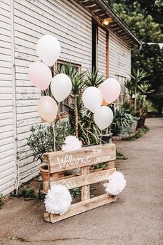 a welcome sign with balloons and pom poms