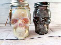 two mason jars with skulls in them are sitting on a table next to each other