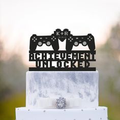 a wedding cake topper with two video game controllers on it