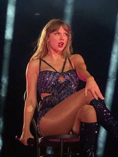 a woman sitting in a chair with her legs crossed and wearing thigh high boots, on stage