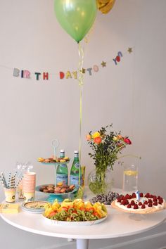 a birthday party with cake, fruit and balloons