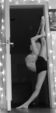 a woman is doing a handstand in front of a mirror with lights on it