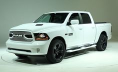 a white ram truck is on display in a showroom with gray walls and black rims