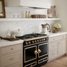 a stove top oven sitting inside of a kitchen next to white cabinets and counter tops