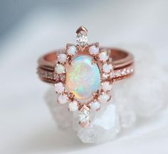 an opal and diamond ring is shown on top of a crystal rock with white stones