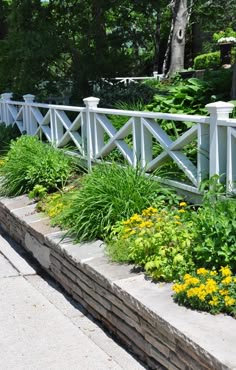 a white fence surrounded by flowers and greenery