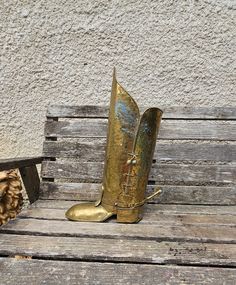 a gold boot sitting on top of a wooden bench next to a pile of wood