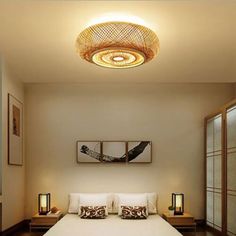 a white bed sitting under a ceiling light in a bedroom