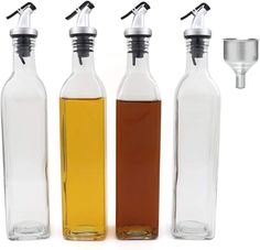 three glass bottles with different types of liquid in them and one empty bottle next to it