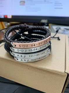 three leather bracelets with personalized names on them sitting in front of a computer