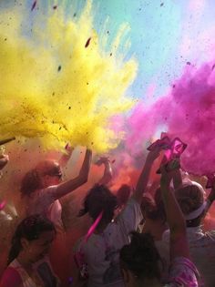 many people are throwing colored powder at each other in the air as they dance and play