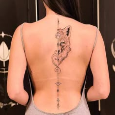 the back of a woman's neck with a fox and arrow tattoo on it