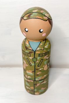 a wooden toy with a soldier's uniform painted on the front and back, sitting on a white surface