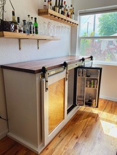 an open refrigerator in the corner of a room with shelves and bottles on the wall