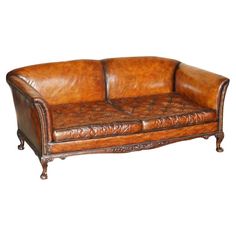 a brown leather couch sitting on top of a white floor next to a wooden frame