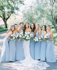 a group of women standing next to each other holding bouquets in their hands and posing for the camera