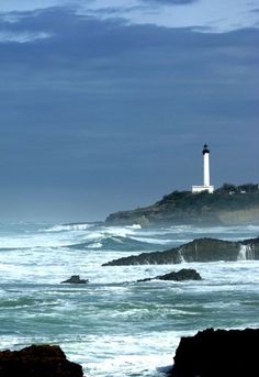 a lighthouse on top of a rocky outcropping next to the ocean with waves