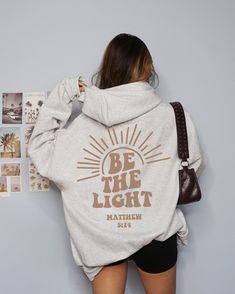 Shine bright in our "Be The Light" Sunset Hoodie--a stylish blend of faith and fashion. With Matthew 5:14 Scripture, this trendy Christian sweatshirt is perfect for summer vibes and spreading Jesus' message. Wrap yourself in faith and warmth--get yours now! This Would Make a Great Gift For your Christian friends and family.  💕MADE WITH DTG * P R I N T I N G  Designs are printed directly on the garment using DTG (direct to garment) to ensure a long-lasting, vibrant & durable finish. The process Sunset Hoodie, Light Sunset, Vsco Hoodie, Light In The Darkness, Matthew 5, Her And Him, Christian Friends