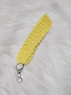 a yellow crochet keychain is laying on a white fur covered surface