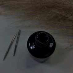 a black vase sitting on top of a white table next to a pair of scissors