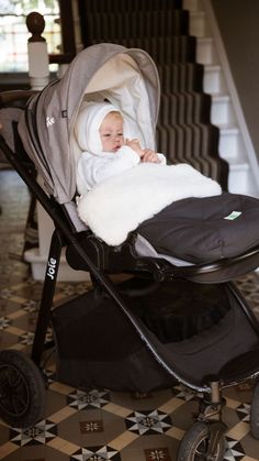 a baby in a stroller with a blanket on it's back, sitting next to some stairs