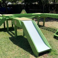 a green play set with a slide in the middle and two benches on each side