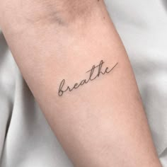 a woman's arm with the word breathe tattooed in cursive writing on it