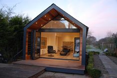 a small house sitting on top of a wooden deck next to a garden area with an open door