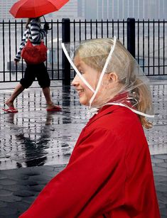 a woman in a red raincoat is holding an umbrella