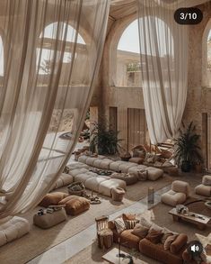 a living room filled with lots of couches and windows covered in white drapes