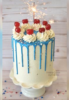 a birthday cake with white frosting and blue sprinkles, topped with a sparkler