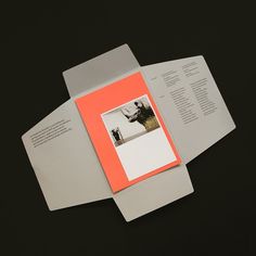 an orange and white brochure is laying on top of some gray papers,