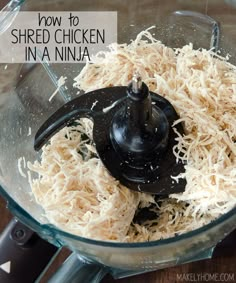 shredded cheese in a food processor with a black lid on a wooden table top, ready to be blended