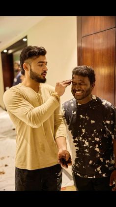 two men standing next to each other brushing their teeth