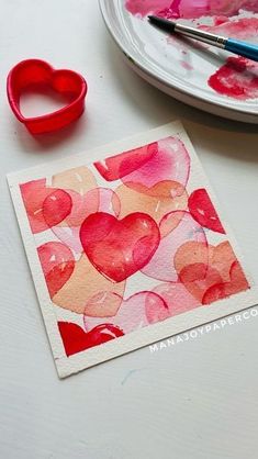 a heart shaped card next to a pair of scissors and a plate with hearts on it