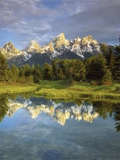 the mountains are reflected in the still water