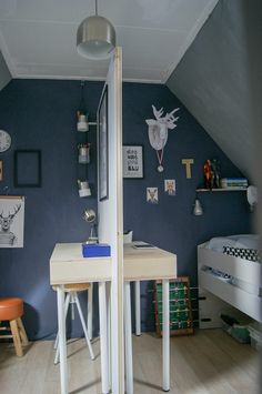 an attic bedroom with blue walls and white desks in the corner is decorated with deer heads