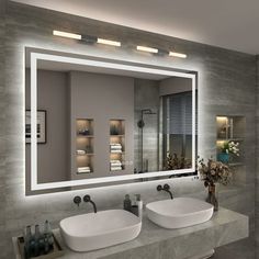 a bathroom with two sinks and a large mirror over it's sink area that is illuminated by lights