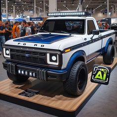 a white and blue truck on display at a car show with people standing around it