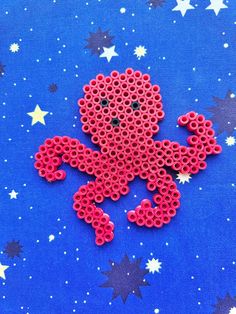 an octopus made out of perler beads on a blue surface with stars in the background