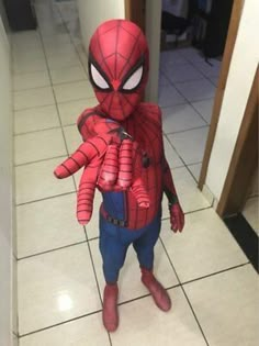 a young boy dressed as spider - man stands in the hallway