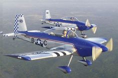 two planes flying side by side in the air with checkered flags on their wings