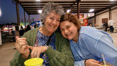 two women sitting at a table with drinks in front of them and smiling for the camera