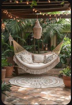 a white hammock hanging from a ceiling in a room filled with potted plants