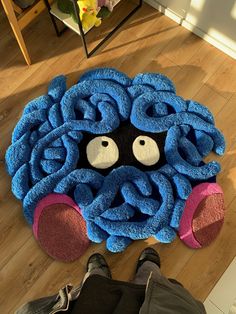 a person standing on the floor in front of a blue rug with an animal's face