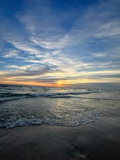 the sun is setting over the ocean with waves coming in