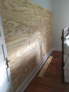 a bed sitting in a bedroom next to a wooden wall with white sheets on it